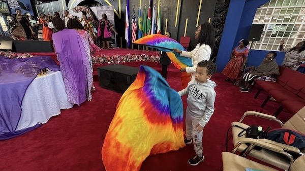 A person and a child holding a rainbow colored fabric