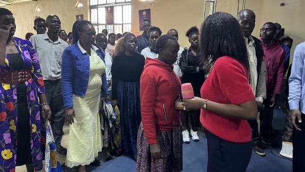 A person holding a microphone to a person in a room with other people