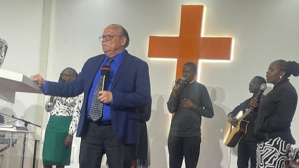 A group of people singing in front of a cross