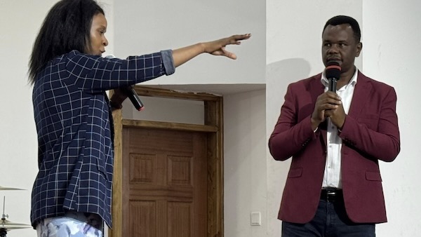 A person holding a microphone and pointing at another person