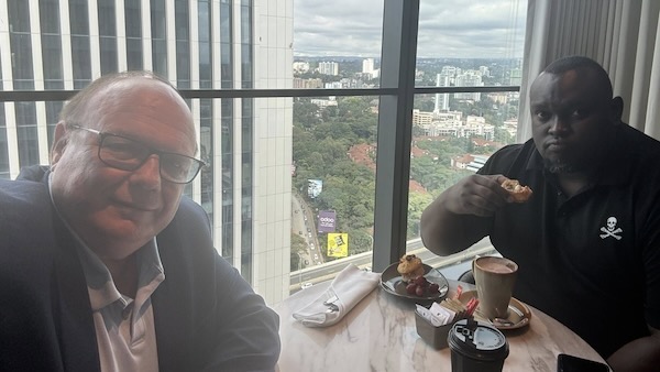 Two men sitting at a table with food