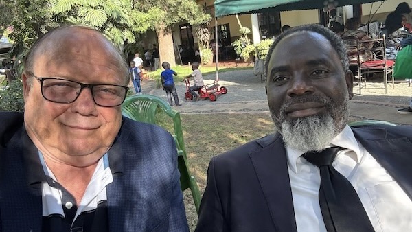 Two men sitting outside smiling for the camera