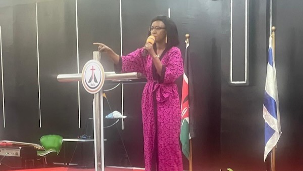 A person in a pink robe speaking into a microphone