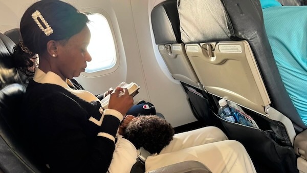 My son sleeping on my wife’s lap on the plane as Adalia is studying the Bible